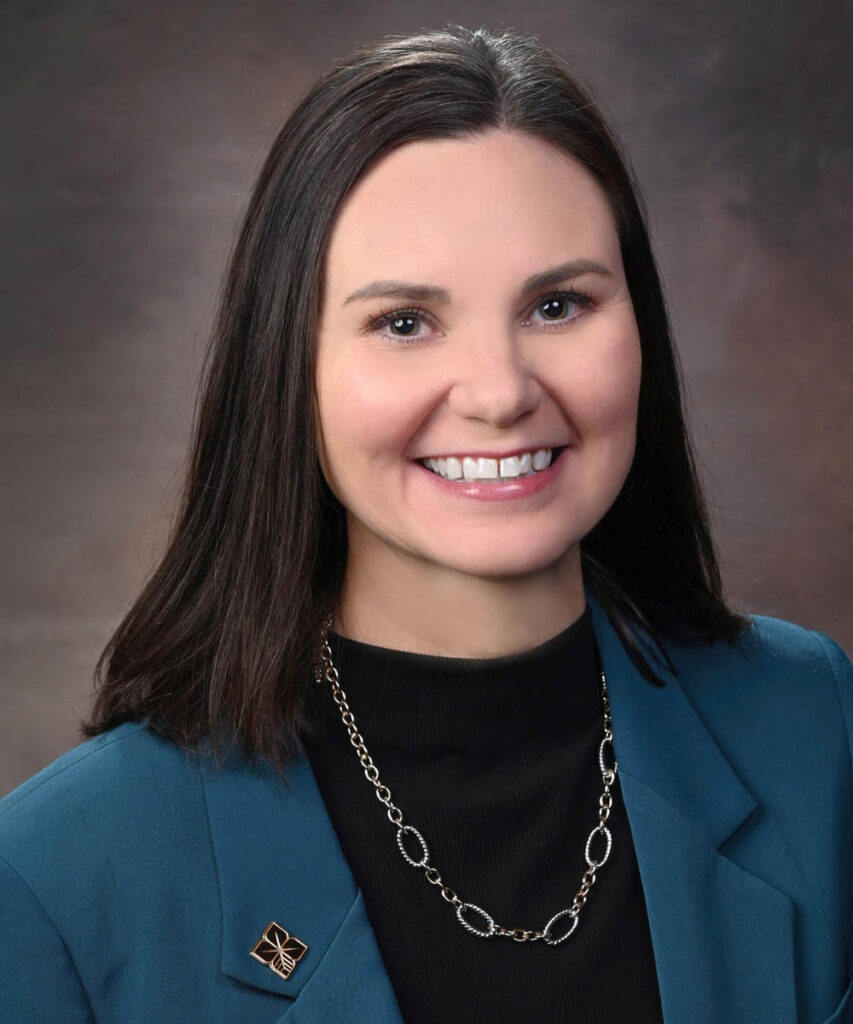 professional head-shot of Kayla Robinson wearing a blue sports coat over a black shirt. She has a biostar pin on her lapel.
