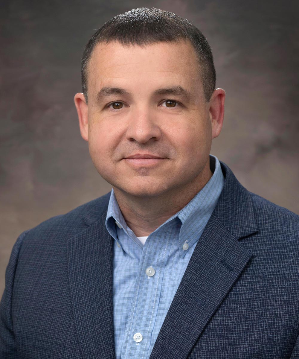 Portrait of Shelby wearing a blue sports-coat and light-blue button-up shirt